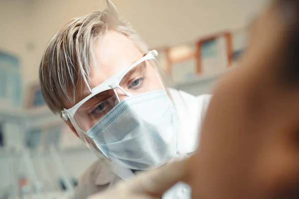 Lekarz w masce medycznej wykonuje zabieg leczenia jamy ustnej u pacjenta — Zdjęcie stockowe