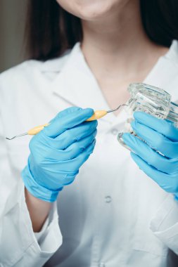 Eldivenli dişçi dişlerin ve kancanın görüntüsünü tutuyor. Sağlıklı gülümseme kavramı