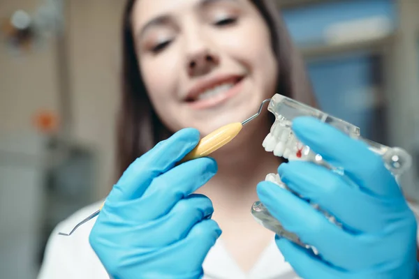 Uśmiechnięty lekarz trzymający model szczęki i urządzenie do czyszczenia zębów. Klinika stomatologiczna — Zdjęcie stockowe