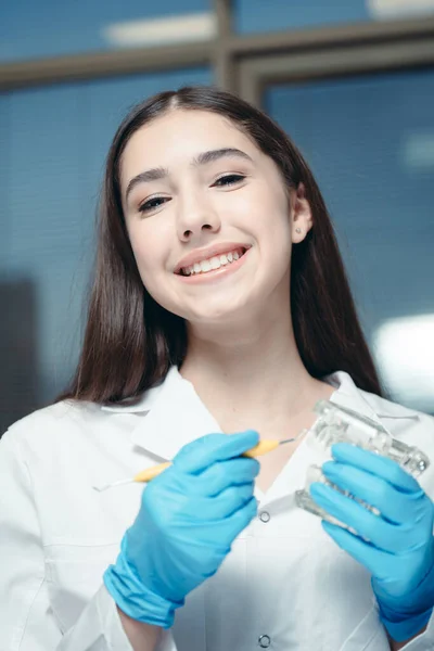 Piękna kobieta w szlafroku medycznym i rękawiczkach ochronnych z modelem jamy ustnej — Zdjęcie stockowe