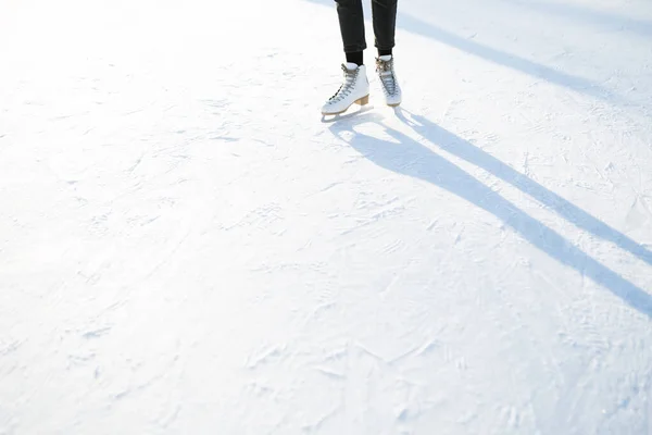 Foto von weiblichen Beinen in weißen Schlittschuhen, die auf Eis Schlittschuh laufen. Winterwochenende-Konzept — Stockfoto