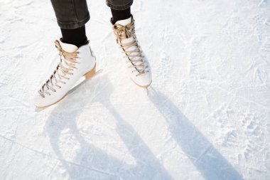 Photo of female legs in white skates that skate on ice. Winter weekend concept clipart