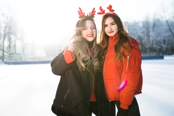 Dos chicas caucásicas con el pelo largo sonriendo a la cámara en el fondo de un bosque de invierno —  Fotos de Stock