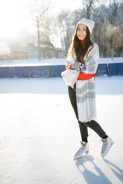 Caucásico chica en un blanco sombrero es patinar en un congelado río en un nevado parque —  Fotos de Stock