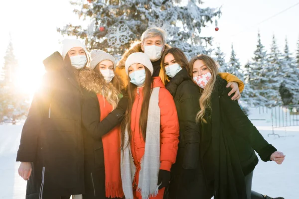 Un grupo de jóvenes con chaquetas y equipo de protección se alza junto al fondo de un árbol de Navidad decorado —  Fotos de Stock