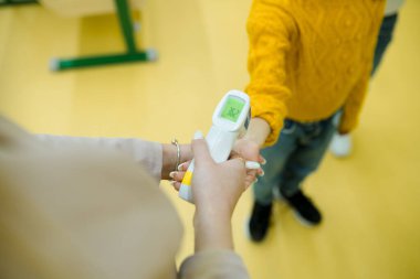 Coronavirüs 'e karşı korunmak için eğitim ortamlarında temas edilmeyen kızılötesi termometre kullanımı