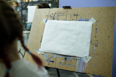 Sınıfta boş bir kağıt parçasıyla duran bir okul sehpası fotoğrafı. Çizim dersi