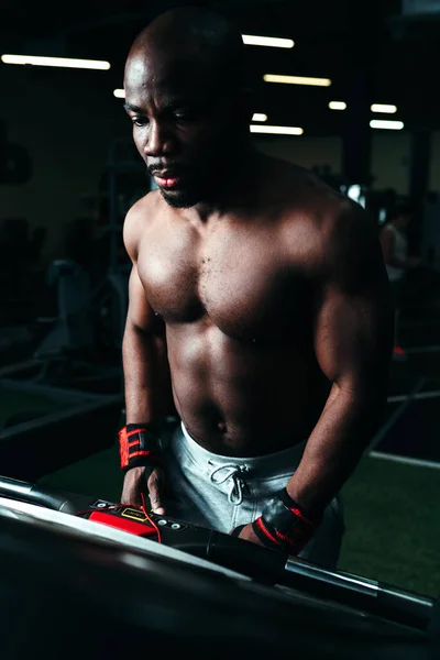 O tipo no ginásio com um corpo atlético corre numa passadeira. Esportes e saúde — Fotografia de Stock