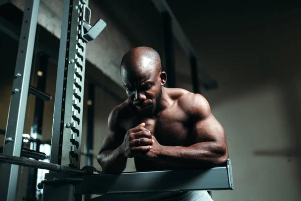 Africano americano homem de calças brancas está sentado no ginásio e se preparando para um treino — Fotografia de Stock