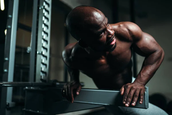 Afrykański Amerykanin w białych spodniach siedzi na siłowni i przygotowuje się do treningu — Zdjęcie stockowe