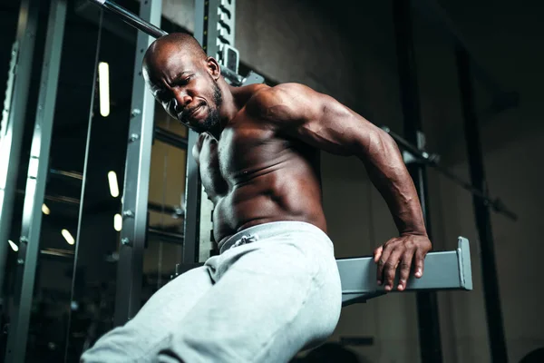 Eşofmanlı çıplak vücutlu kaslı bir adam spor salonunda egzersiz yapıyor. Sağlıklı yaşam tarzı — Stok fotoğraf