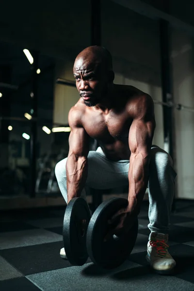 Çıplak gövdeli bir adam ağır halter diskleri tutuyor. Spor malzemelerini kullanarak güç eğitimi — Stok fotoğraf