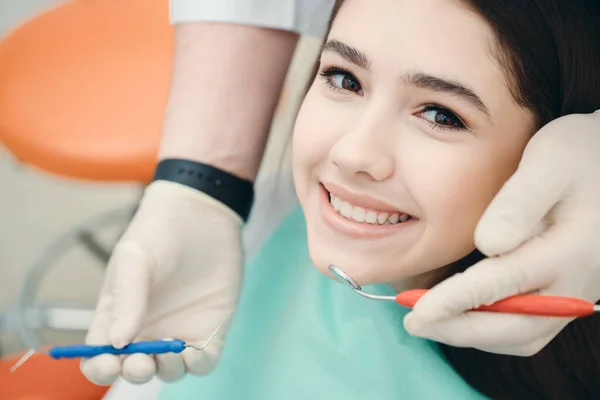 Retrato de uma menina caucasiana perto da qual as mãos do médico com uma sonda dental — Fotografia de Stock