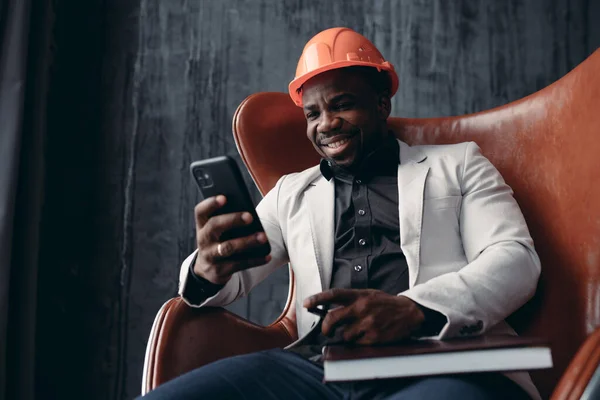 Портрет африканского американца, сидящего в кресле и фотографирующего себя по телефону — стоковое фото