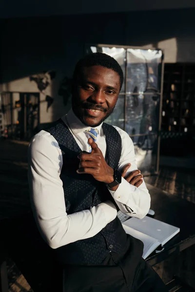Homem americano africano elegante está com os braços cruzados em um fundo escuro sorrindo — Fotografia de Stock