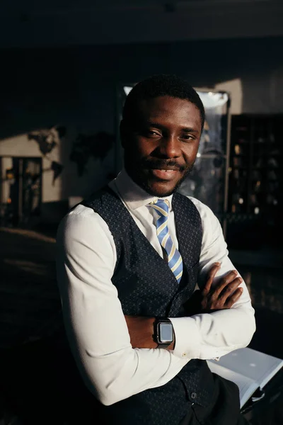 Homem americano africano elegante está com os braços cruzados em um fundo escuro sorrindo — Fotografia de Stock