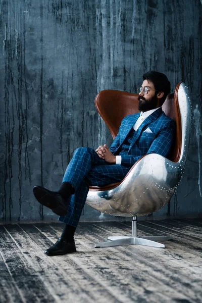 黒い髭を生やしたスタイリッシュなひげが椅子に座り、カメラを見る。 — ストック写真