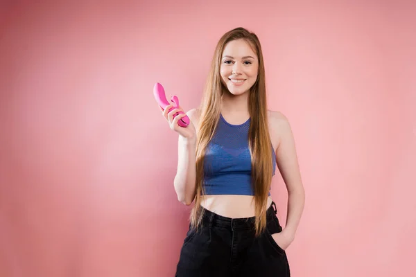 The girl holds a pink massager for sex in her hands. Vibrator for masturbation. Image for sex top. Attractive girl with dildo on pink background — Stock Fotó