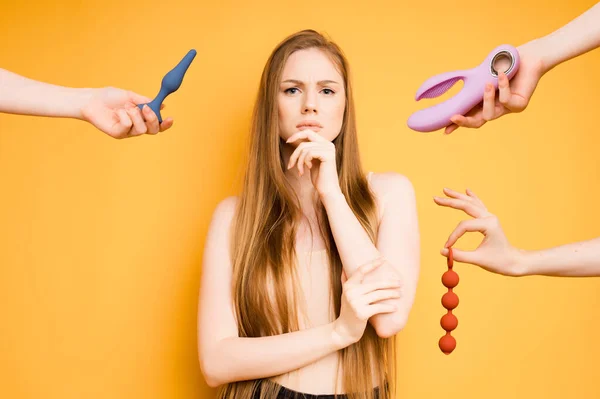 Die Kaukasierin porträtiert einen nachdenklichen Blick auf eine Fülle von Dildos oder Klitorismännern. Auswahl an Spielzeug für Erwachsene, Sexshop-Konzept — Stockfoto