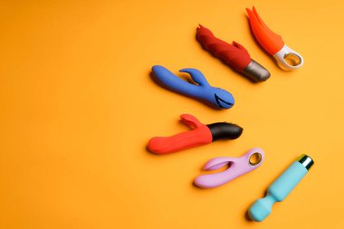 Sarı arka planda çok renkli dildoların bolluğu. Klitoris masaj aleti, kadın sağlığını korumak için seks oyuncakları. Metin için boşluk