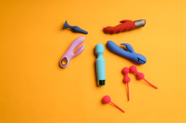 Sarı arka planda çok renkli dildolar ve kegel topları bolluğu. Klitoris masaj aleti, kadın sağlığını korumak için seks oyuncakları. Metin için boşluk