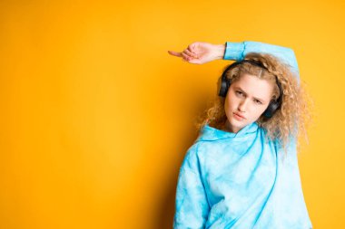 Kıvırcık saçlı ve kulaklıklı genç bir kız yan tarafı işaret ediyor. Yazıtlar için yer