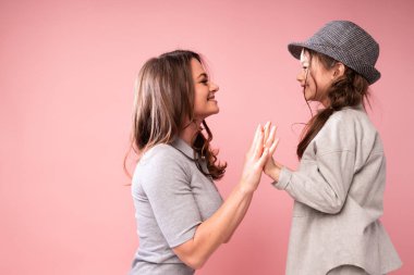 Sevimli anne, tatlı gülümseyen kızının yanına oturur ve onunla pasta oynar.