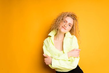 Açık renk ceketli çekici bir kız kollarını göğsünde kavuşturdu ve kameraya baktı.