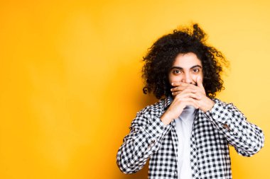 Ekose gömlekli neşeli Mısırlı avuçlarıyla ağzını kapatıyor.