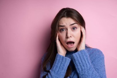 Diş teli olan beyaz bir kız pembe arka planda duyguları resmediyor. Diş telleri takıldıktan sonra ağrı