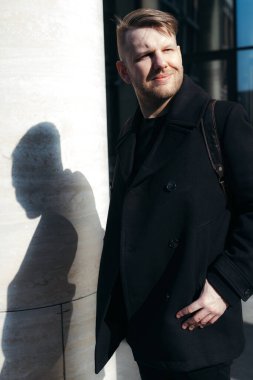 Sırt çantalı yakışıklı, güneş ışığında gülümseyen bir adam.