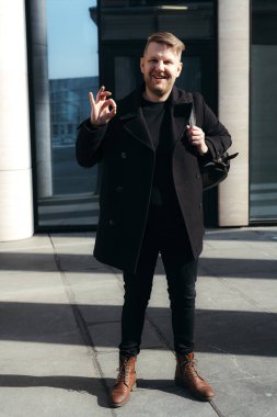 Sırt çantalı neşeli öğrenci sınavın mükemmel sonucuna seviniyor. Parmaklarıyla işaret veriyor.