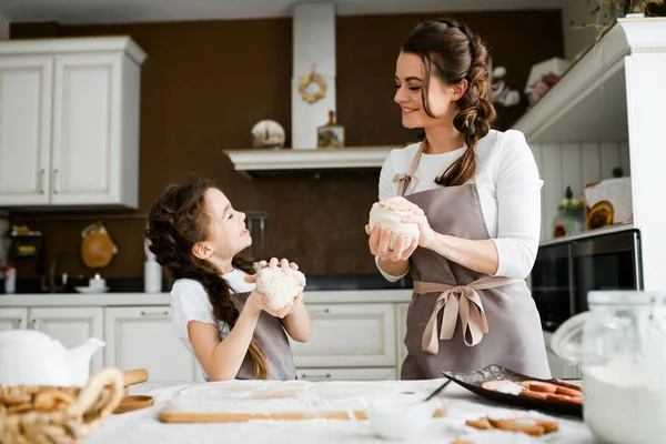 Premium Photo  Beautiful mom and daughter in aprons are adding milk to  flour and smiling while using making cookies at home