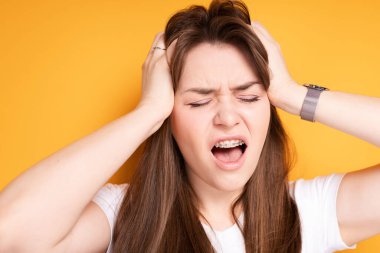 Uzun saçlı tatlı esmer, diş tellerini taktıktan sonra ellerini acıdan uzak tutuyor.