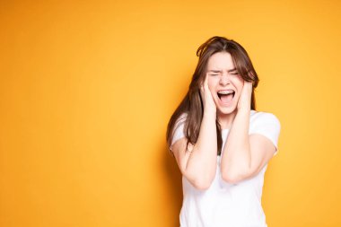 Beyaz tişörtlü kızgın kız diş tellerinin takılması yüzünden dişleri ağrıyıp bağırıyor.