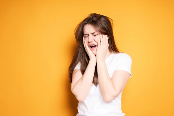 Krásná dívka v bílém tričku křičí bolestí v zubech po instalaci rovnátka — Stock fotografie