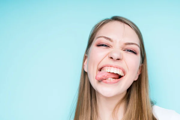 Atraktivní dívka si pohrává s otevřenými ústy a vystrkuje jazyk mrkáním — Stock fotografie