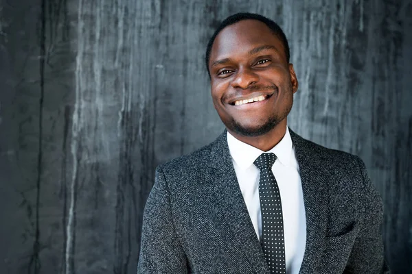 Retrato de um feliz empresário afro-americano alegre em um terno que está sorrindo para a câmera — Fotografia de Stock