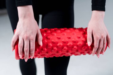 Close-up. Female hands with a red massage roll to work out the fascia. Pilates equipment concept