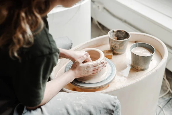 Faire un vase en argile sur une roue de potiers. mains féminines dans le cadre — Photo