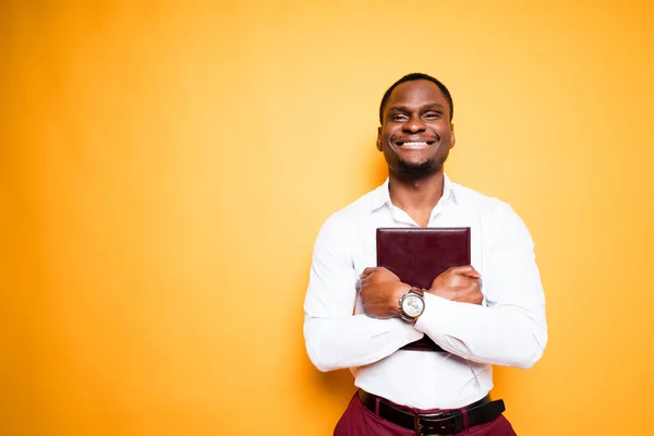 Happy african american student holding textbook smiling and looking at camera — Fotografia de Stock