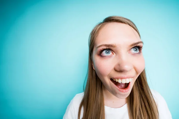 Fotografia de perto. Menina bonita feliz sorri amplamente enquanto está de pé sobre um fundo azul. Olho de peixe — Fotografia de Stock