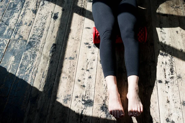 Foto de piernas femeninas haciendo ejercicios para fortalecer los músculos de las piernas usando la fascia mientras está sentado en el suelo — Foto de Stock