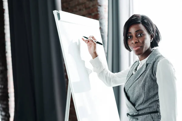 Beautiful african american businesswoman presenting her idea by drawing a drawing on a white board