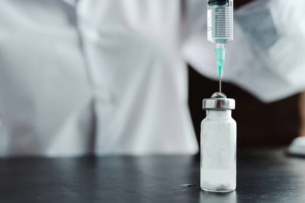 Фото крупным планом. Доктор в белом халате принимает вакцину со шприцем — стоковое фото