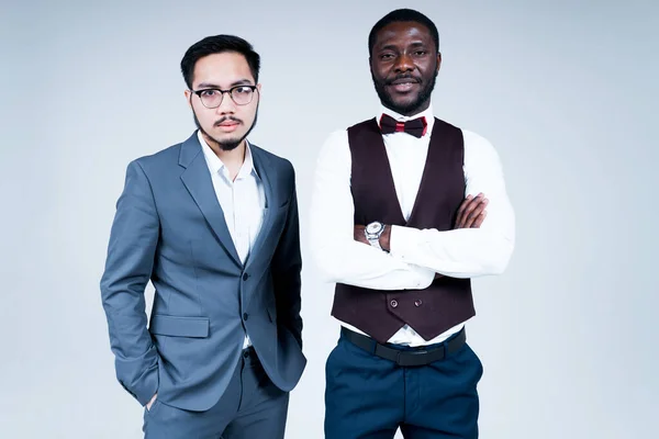 Κομψό σοβαρή αφροαμερικανοί και ασιάτες επιχειρηματίες κοιτάζοντας κάμερα, ενώ στέκεται σε γκρι φόντο — Φωτογραφία Αρχείου