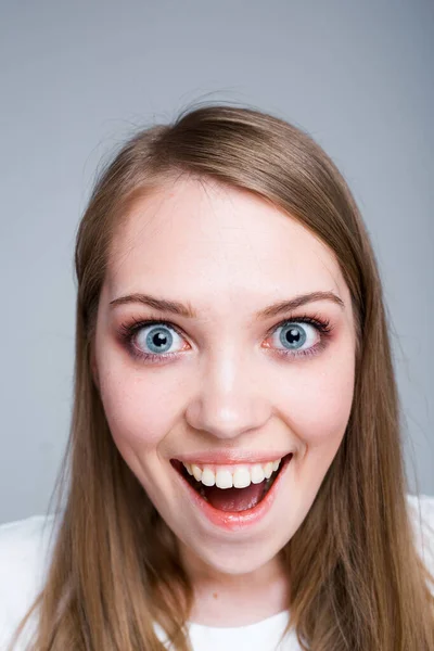 Фото крупным планом. Портрет молодой счастливой девушки, которая с удивлением открывает рот и смотрит в камеру — стоковое фото