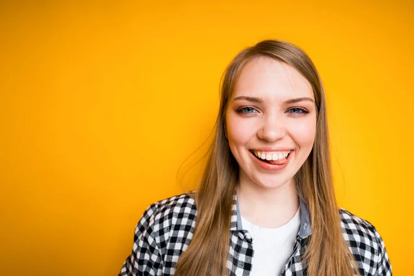 Joyeux jeune fille en chemise souriant et riant montrant dents blanches et debout sur fond jaune — Photo