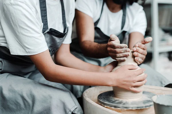 Une fille et un homme en tabliers dans un atelier d'argile. Les mains masculines et féminines font des vases en argile — Photo