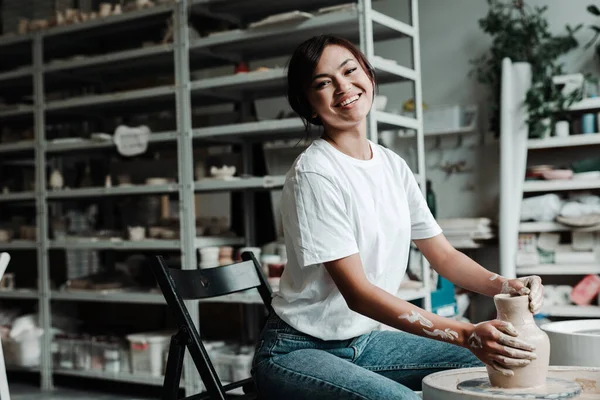 Mooi gelukkig aziatisch meisje het maken van een klei vaas in een workshop glimlachen en kijken naar de camera — Stockfoto